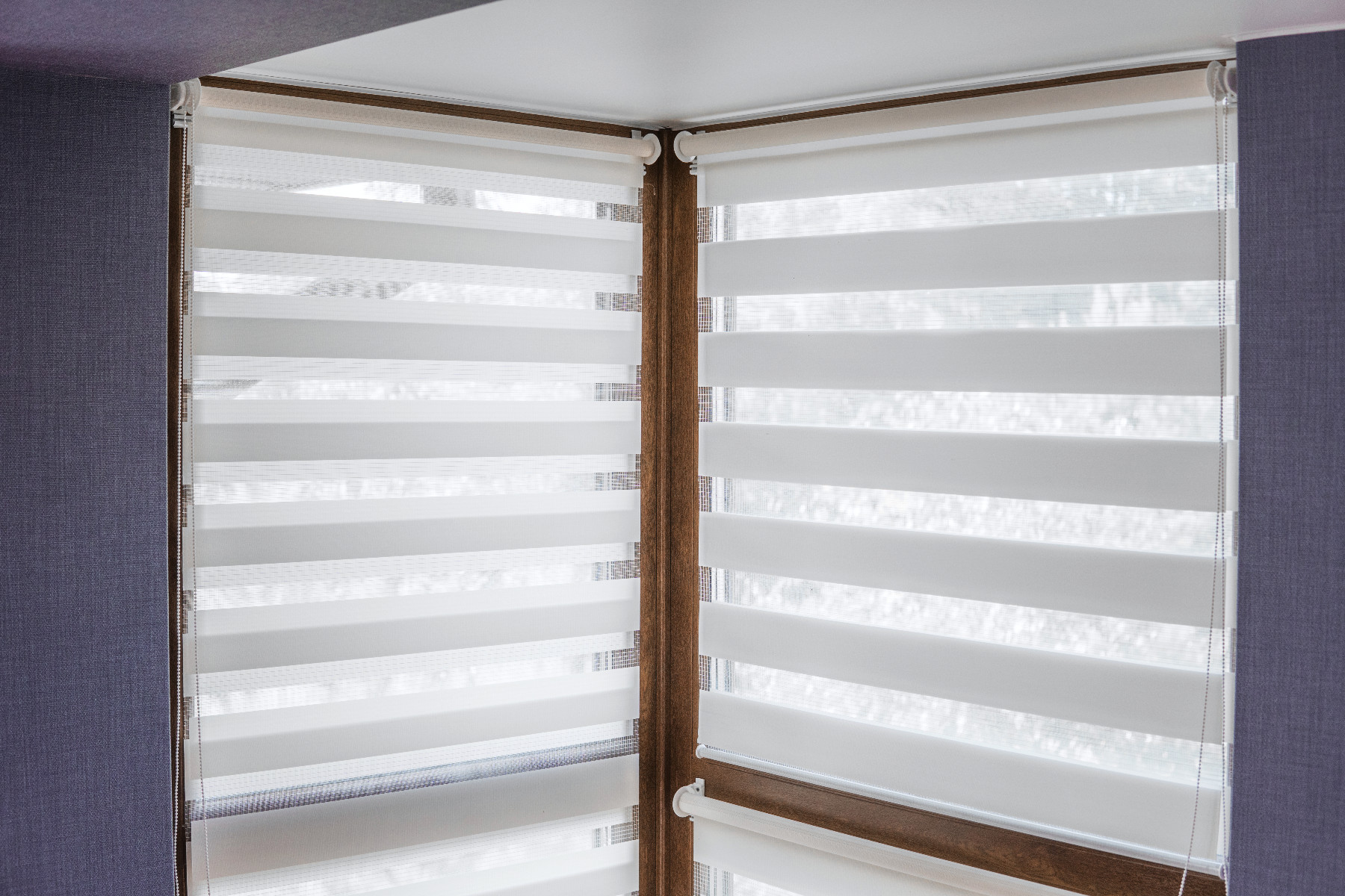 White fabric roller blinds on the plastic window with wood texture in the living room with blue wall.